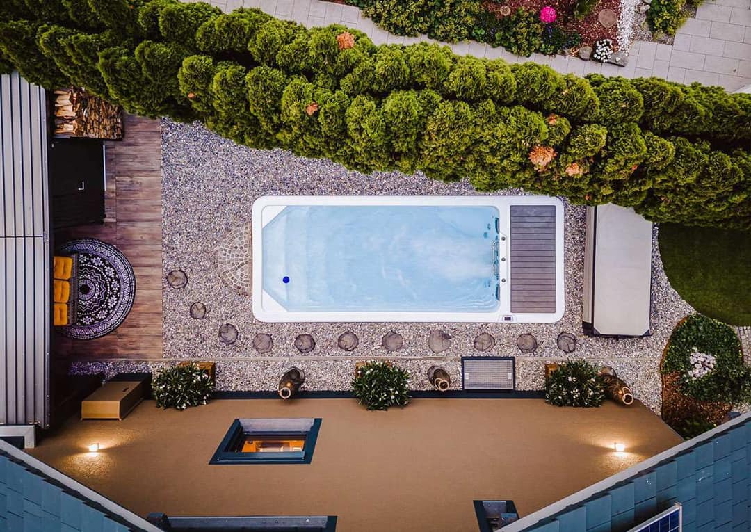 Swimspa in einem Kiesbett mit Trittsteinen und Holzdeck, von oben gesehen