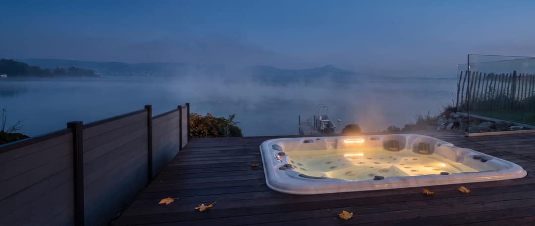 In eine Holzterrasse eingelassener Whirlpool am See, Nebel in der Abenddämmerung