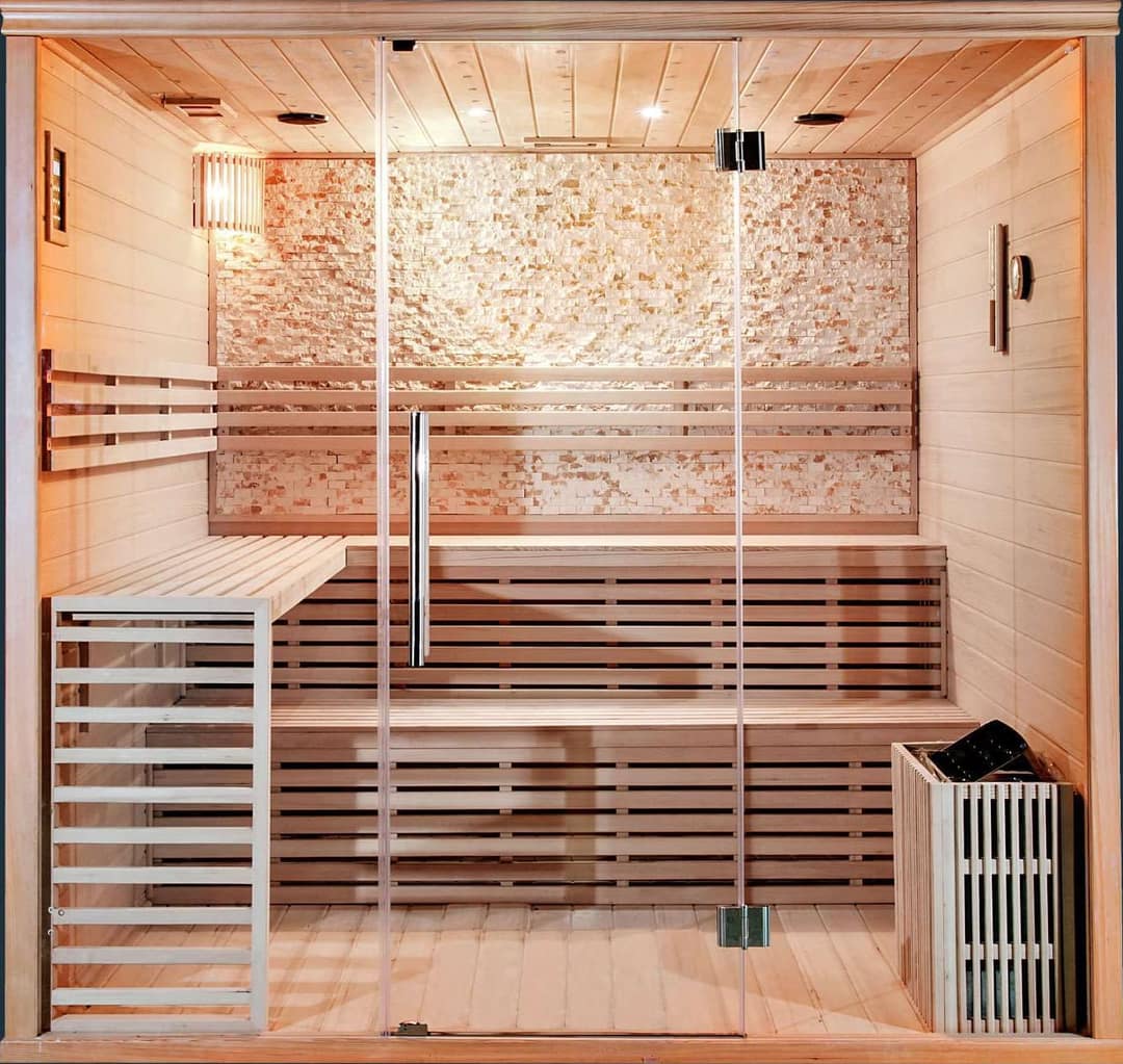 Innensauna aus hellem Holz mit Glastür, Bänken und Saunaofen
