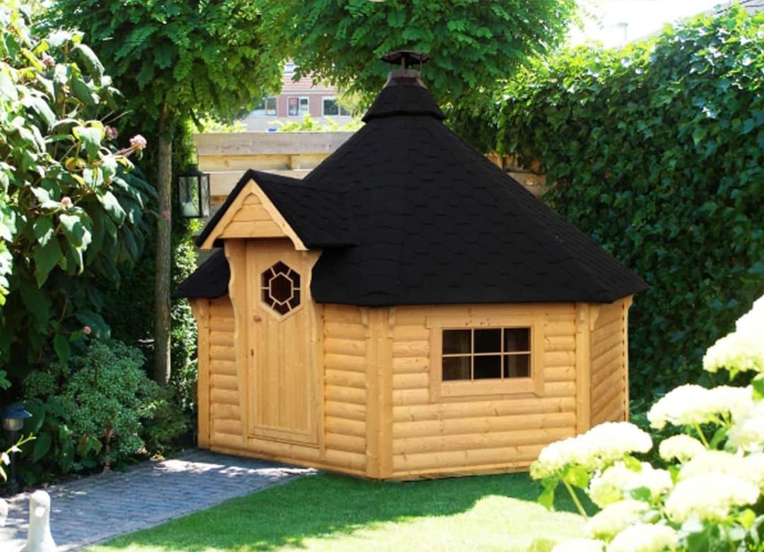 Sechseckiges Saunahaus aus hellem Holz mit schwarzem Schindeldach in einem Garten