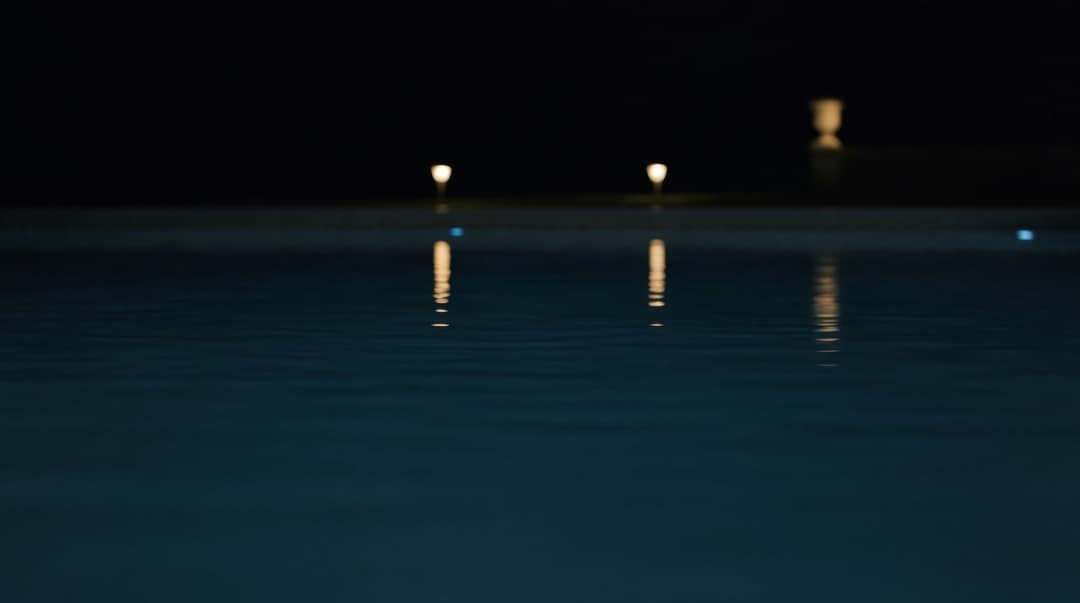 Pool bei Nacht, im dunklen Wasser spiegeln sich Gartenlichter