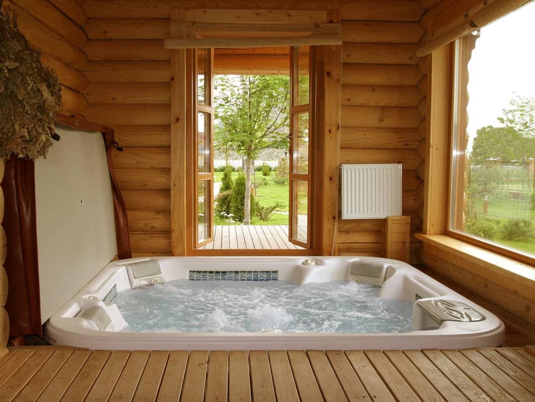 In einen Holzboden eingelassener Whirlpool in einem Wellnessraum aus Holz